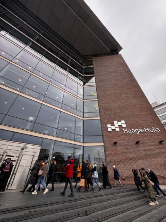 Grupa osób wchoidzi po schodach do budynku Uniwersytetu Nauk Stosowanych Haaga Helia