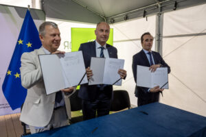 Mężczyźni trzymający w dłoniach podpisane porozumienia